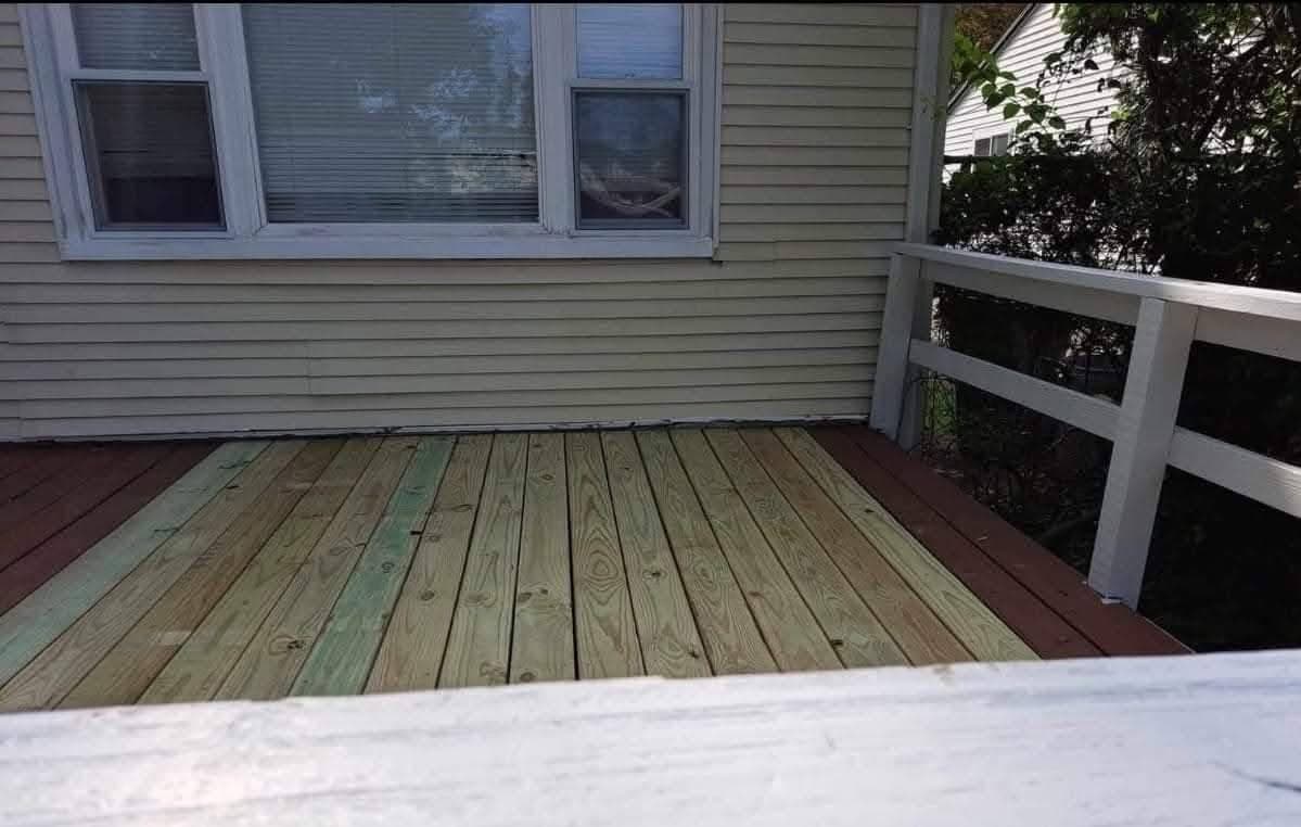 New light-colored wooden planks installed on a dark brown deck with a white railing.
